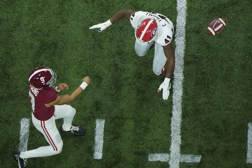 Alabama&#39;s Bryce Young thorws past Georgia&#39;s Channing Tindall during the first half of the College Football Playoff championship football game Monday, Jan. 10, 2022, in Indianapolis. (AP Photo/Charlie Riedel)