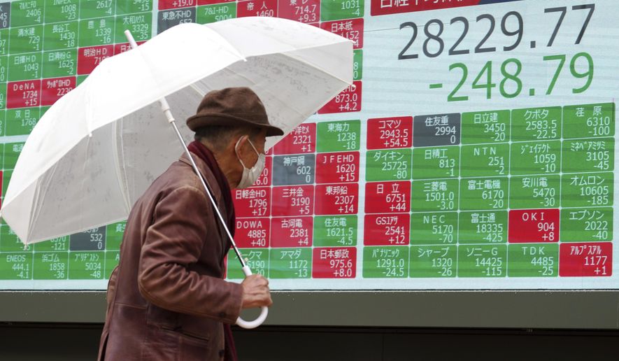 A man wearing a protective mask looks at an electronic stock board showing Japan&#39;s Nikkei 225 index at a securities firm Tuesday, Jan. 11, 2022, in Tokyo. Asian shares sank in cautious trading Tuesday following a decline on Wall Street amid continuing worries about the omicron coronavirus variant, especially rising cases in China. (AP Photo/Eugene Hoshiko)