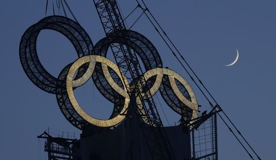 A worker labors to assemble the Olympic Rings onto of a tower on the outskirts of Beijing, China on Jan. 5, 2022. The Beijing Winter Olympics are fraught with potential hazards for major sponsors, who are trying to remain quiet about China&#39;s human rights record while protecting at least $1 billion they&#39;ve paid to the IOC. (AP Photo/Ng Han Guan, File) **FILE**