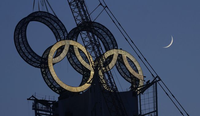 A worker labors to assemble the Olympic Rings onto of a tower on the outskirts of Beijing, China on Jan. 5, 2022. The Beijing Winter Olympics are fraught with potential hazards for major sponsors, who are trying to remain quiet about China&#x27;s human rights record while protecting at least $1 billion they&#x27;ve paid to the IOC. (AP Photo/Ng Han Guan, File) **FILE**