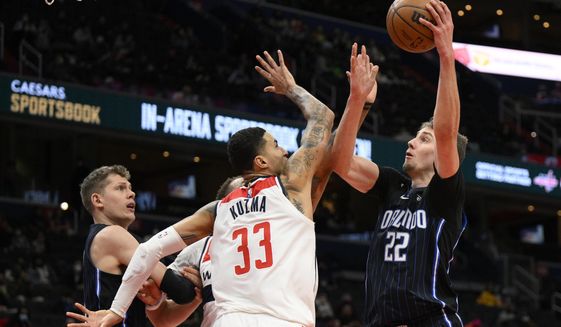 Orlando Magic forward Franz Wagner (22) goes to the basket against Washington Wizards forward Kyle Kuzma (33) during the first half of an NBA basketball game, Wednesday, Jan. 12, 2022, in Washington. Magic center Moritz Wagner watches at left. (AP Photo/Nick Wass)