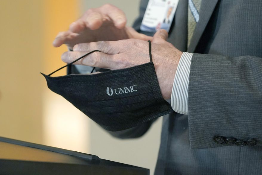 FILE - Dr. Alan Jones, associate vice chancellor for clinical affairs and COVID-19 clinical response leader, holds a face mask as he answers questions about the spread of the omicron variant during a news briefing at the University of Mississippi Medical Center School of Medicine in Jackson, Miss., Jan. 11, 2022. Officials across the U.S. are again weighing how and whether to impose mask mandates as COVID-19 infections soar and the American public grows weary of pandemic-related restrictions. (AP Photo/Rogelio V. Solis, File)