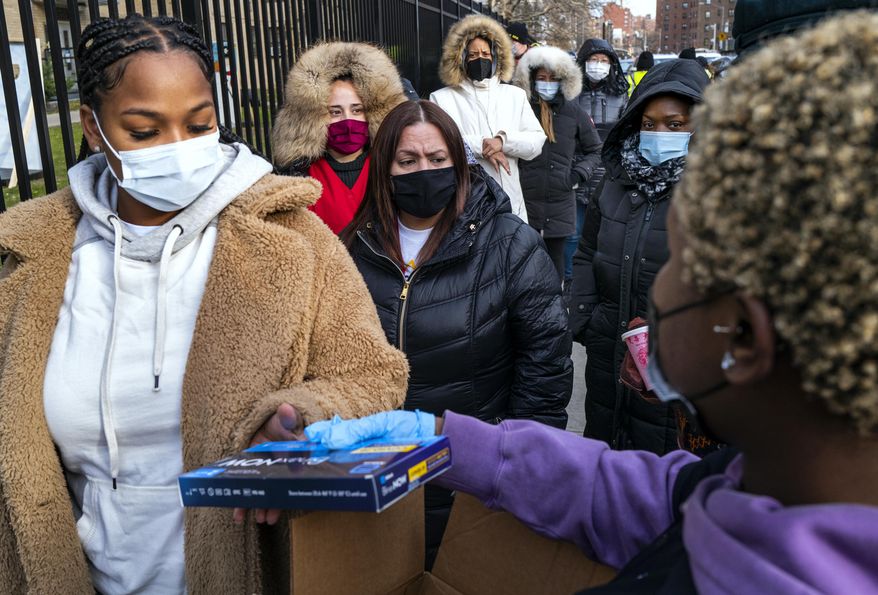 People line up and receive test kits to detect COVID-19 as they are distributed in New York on Dec. 23, 2021. The COVID-19 surge caused by the omicron variant means once-reliable indicators of the pandemic's progress are much less so, complicating how the media is able to tell the story. (AP Photo/Craig Ruttle, File)