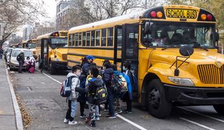 Students wearing masks board a school bus outside New Explorations into Science, Technology and Math school, in the Lower East Side neighborhood of New York, Dec. 21, 2021. In a reversal, New York Mayor Eric Adams is considering a remote option for schools. (AP Photo/Brittainy Newman, File)