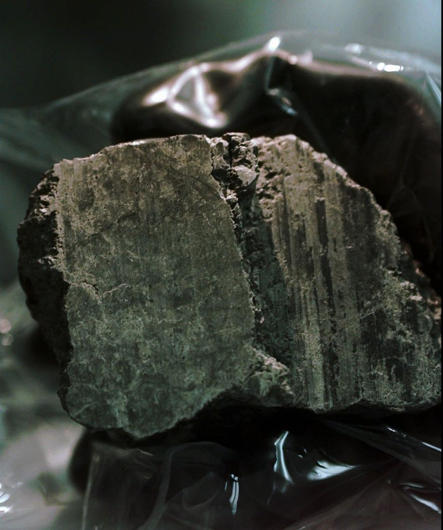 The meteorite labeled ALH84001 is held in the hand of a scientist at a Johnson Space Center lab in Houston, Aug. 7, 1996. Scientists say they've confirmed the meteorite from Mars contains no evidence of ancient Martian life. The rock caused a splash 25 years ago when a NASA-led team announced that its organic compounds may have been left by living creatures, however primitive. Researchers chipped away at that theory over the decades. A team of scientists led by Andrew Steele of the Carnegie Institution published their findings Thursday, Jan. 13, 2022. (AP Photo/David J. Phillip)