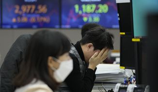 A currency trader covers his face with his hands at the foreign exchange dealing room of the KEB Hana Bank headquarters in Seoul, South Korea, Thursday, Jan. 13, 2022. Shares were mostly lower in Asia on Wednesday after the latest report of surging prices in the U.S. appeared to keep the Federal Reserve on track to raise interest rates in coming months.(AP Photo/Ahn Young-joon)