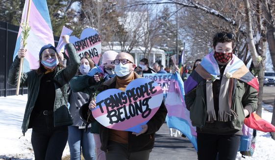 FILE - Advocates for transgender people march from the South Dakota governor&#39;s mansion to the Capitol in Pierre, S.D., on March 11, 2021. A South Dakota legislative committee on Friday, Jan. 14, 2022 approved a bill championed by Gov. Kristi Noem to ban transgender women and girls from participating in school sports leagues that match their gender identity. (AP Photo/Stephen Groves, File)