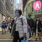 People walk across a street in Hong Kong, Tuesday, Jan. 11, 2022. In an effort to limit omicron outbreaks, Hong Kong is closing kindergartens and primary schools after infections were reported in students, city leader Carrie Lam said Tuesday. Schools are to close by Friday and remain shut until at least the Lunar New Year holiday in the first week of February. (AP Photo/Kin Cheung)