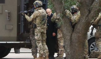 Shortly after 5 p.m., local time, authorities escort a hostage out of the Congregation Beth Israel synagogue in Colleyville, Texas, Saturday, Jan. 15, 2022. Police said the man was not hurt and would be reunited with his family. (Elias Valverde/The Dallas Morning News via AP)