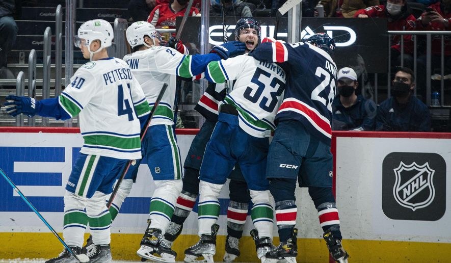 Washington Capitals right wing Garnet Hathaway (21) gets into a scrum with Vancouver Canucks center Bo Horvat (53), as Capitals center Nic Dowd (26) and Canucks defenseman Luke Schenn (2) try to pull them off during the second period of an NHL hockey game against the Vancouver Canucks, Sunday, Jan. 16, 2022, in Washington. (AP Photo/Al Drago)