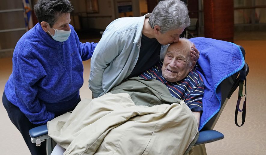 Melvin Goldstein, 90, smiles as his daughter Barbara Goldstein gives him a kiss on the head during their first in-person, indoor family visit inside the Hebrew Home at Riverdale, March 28, 2021, in the Bronx borough of New York. COVID-19 infections are soaring again at U.S. nursing homes because of the omicron wave, and deaths are climbing too. That&#x27;s leading to new restrictions on family visits and a renewed push to get more residents and staff members vaccinated and boosted. (AP Photo/Kathy Willens) **FILE**