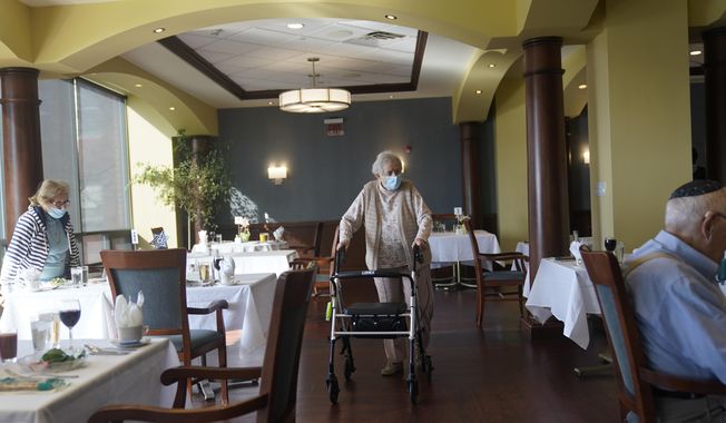 May Nast arrives for dinner at RiverWalk, an independent senior housing facility, in New York, April 1, 2021. COVID-19 infections are soaring again at U.S. nursing homes because of the omicron wave, and deaths are climbing too. That&#x27;s leading to new restrictions on family visits and a renewed push to get more residents and staff members vaccinated and boosted. (AP Photo/Seth Wenig, File)