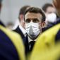 French President Emmanuel Macron, wearing a protective face mask and a working helmet, talks with workers of the WEurope platform by German chemical giant BASF during a visit at the Alsachimie industrial site in Chalampe, eastern France, as part of a day trip on the economic attractiveness and reindustrialization of France, Monday, Jan. 17, 2022. (Benoit Tessier, Pool Photo via AP)