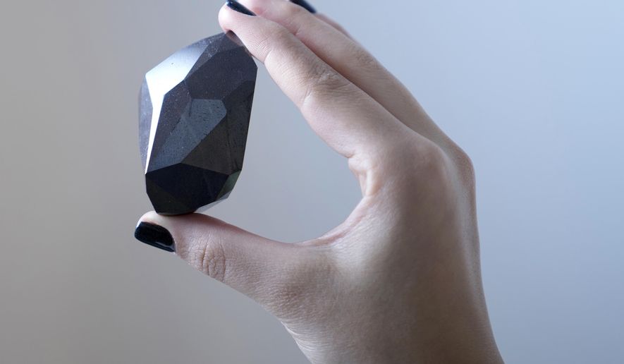 An employee of Sotheby&#39;s Dubai presents a 555.55 Carat Black Diamond &amp;quot;The Enigma&amp;quot; to be auctioned at Sotheby&#39;s Dubai gallery, in Dubai, United Arab Emirates, Monday, Jan. 17, 2022. (AP Photo/Kamran Jebreili)