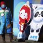 A woman wearing a face mask to protect against COVID-19 stands next to figures of the Winter Paralympic mascot Shuey Rhon Rhon left, and Winter Olympic mascot Bing Dwen Dwen on a pedestrian shopping street in Beijing, Saturday, Jan. 15, 2022. As the Beijing Winter Olympics loom, the Chinese capital is stepping measures to keep the coronavirus at bay including suspending most access to Tianjin, an adjacent major city which is dealing with an outbreak of the highly contagious omicron variant. These outbreaks are posing a test to its &amp;quot;zero-tolerance&amp;quot; COVID-19 policy and its ability to successfully host the Winter Olympics. (AP Photo/Mark Schiefelbein)