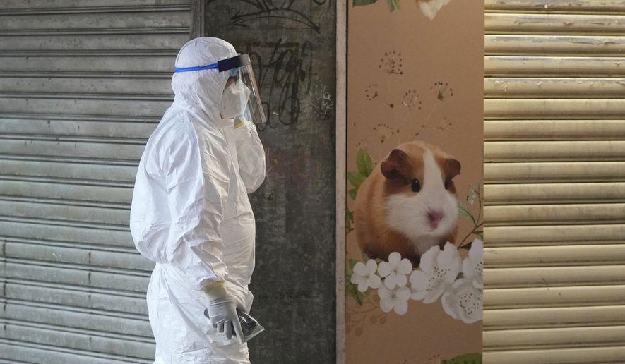 A staffer from the Agriculture, Fisheries and Conservation Department walks past a pet shop that was closed after some pet hamsters were, authorities said, tested positive for the coronavirus, in Hong Kong, Tuesday, Jan. 18, 2022. (AP Photo/Kin Cheung)
