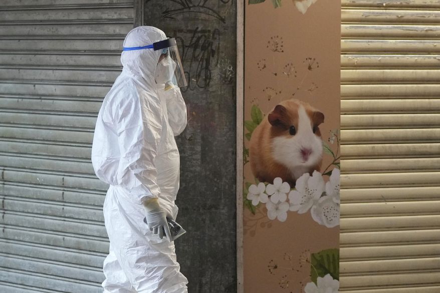 A staffer from the Agriculture, Fisheries and Conservation Department walks past a pet shop that was closed after some pet hamsters were, authorities said, tested positive for the coronavirus, in Hong Kong, Tuesday, Jan. 18, 2022. (AP Photo/Kin Cheung)
