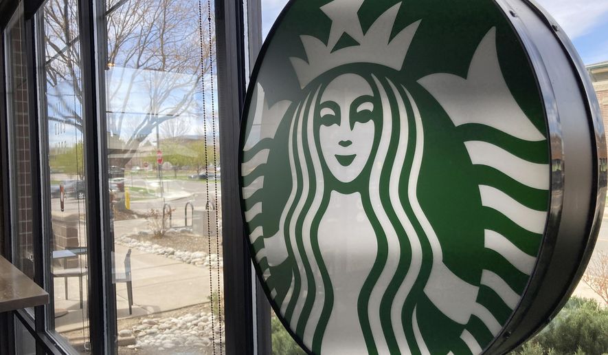 A sign bearing the corporate logo hangs in the window of a Starbucks open only to take-away customers in this photograph taken Monday, April 26, 2021, in southeast Denver.  Starbucks is no longer requiring its U.S. workers to be vaccinated against COVID-19, reversing a policy it announced earlier this month. The Seattle coffee giant says, Wednesday, Jan. 19, 2022,  it&#39;s responding to last week’s ruling by the U.S. Supreme Court.  (AP Photo/David Zalubowski)