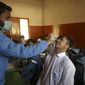 A heath worker takes a nasal swab sample from a student to test for the coronavirus at a school, in Karachi, Pakistan, Wednesday, Jan. 19, 2022. (AP Photo/Fareed Khan)