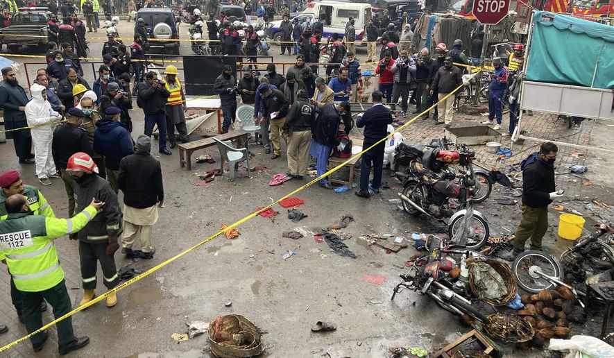 Police officials examine the site of a bomb explosion, in Lahore, Pakistan, Thursday, Jan. 20, 2022. Police said the powerful bomb exploded in a crowded bazaar in Pakistan’s second-largest city of Lahore, killing several people and wounding dozens of others. (AP Photo/K.M. Chaudary)