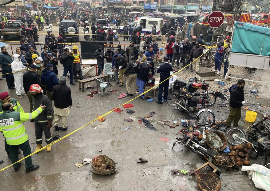 Police officials examine the site of a bomb explosion, in Lahore, Pakistan, Thursday, Jan. 20, 2022. Police said the powerful bomb exploded in a crowded bazaar in Pakistan’s second-largest city of Lahore, killing several people and wounding dozens of others. (AP Photo/K.M. Chaudary)