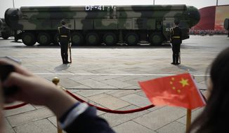 Spectators wave Chinese flags as military vehicles carrying DF-41 ballistic missiles roll during a parade to commemorate the 70th anniversary of the founding of Communist China in Beijing, Tuesday, Oct. 1, 2019. China on Friday, Jan. 21, 2022, criticized Washington for imposing sanctions on Chinese companies the U.S. says exported missile technology and accused the United States of hypocrisy for selling nuclear-capable cruise missiles. (AP Photo/Mark Schiefelbein) **FILE**