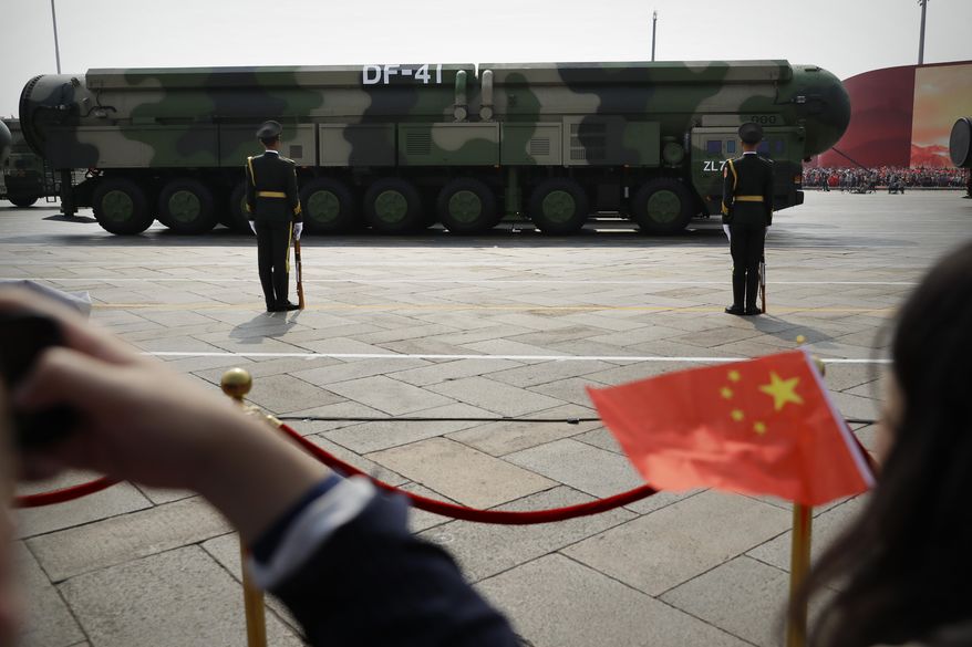 Spectators wave Chinese flags as military vehicles carrying DF-41 ballistic missiles roll during a parade to commemorate the 70th anniversary of the founding of Communist China in Beijing, Tuesday, Oct. 1, 2019. China on Friday, Jan. 21, 2022, criticized Washington for imposing sanctions on Chinese companies the U.S. says exported missile technology and accused the United States of hypocrisy for selling nuclear-capable cruise missiles. (AP Photo/Mark Schiefelbein) **FILE**