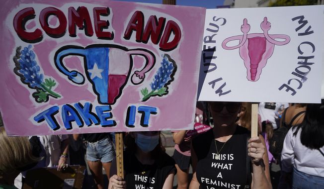 In this file photo, demonstrators rally to demand continued access to abortion during the March for Reproductive Justice, Oct. 2, 2021, in downtown Los Angeles. The sign shown at left plays off a slogan emblazoned on the Gonzales flag flown in the Texas Revolution, &quot;Come and Take It.&quot; (AP Photo/Damian Dovarganes, file) **FILE**