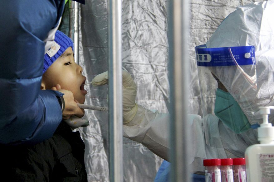 In this photo released by Xinhua News Agency, a child gets a throat swab for the COVID-19 test at a residential area in Fengtai District in Beijing, Sunday, Jan. 23, 2022. People in a Beijing district with some 2 million residents were ordered Sunday to undergo mass coronavirus testing following a series of infections as China tightened anti-disease controls ahead of the Winter Olympics. (Tang Rufeng/Xinhua via AP)