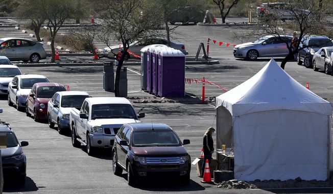 Vehicles, with patients waiting to take a COVID-19 Polymerase Chain Reaction (PCR) test, line up at a testing tent during the Federal Emergency Management Agency&#x27;s drive-through COVID-19 testing site at Pima Community College West Campus in Tucson, Ariz. on Monday, Jan. 24, 2022. After a request from the Pima County Health Department, a drive-through testing site, funded by FEMA region 9, is offering free COVID-19 PCR self-swab tests from 8 a.m. to 6 p.m., Monday through Saturday. (Rebecca Sasnett/Arizona Daily Star via AP)