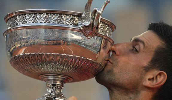 Serbia&#39;s Novak Djokovic kisses the cup after defeating Stefanos Tsitsipas of Greece during their final match of the French Open tennis tournament at the Roland Garros stadium Sunday, June 13, 2021 in Paris. Top-ranked player Novak Djokovic could be allowed to defend his French Open title under the latest COVID-19 rules adopted by the French government, even if he still not vaccinated when the clay-court Grand Slam starts in May. (AP Photo/Michel Euler, File) **FILE**