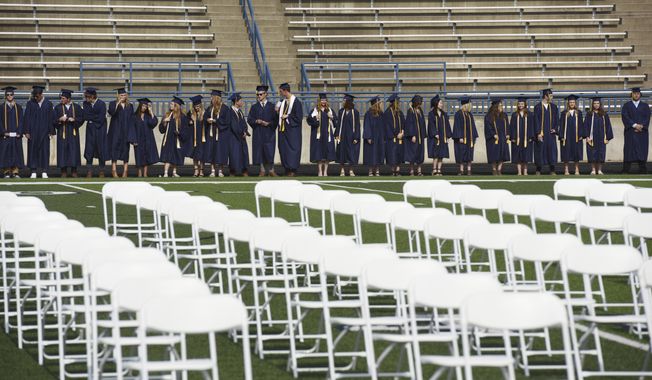 Graduates wait for the start of the St. Joseph High School Class of 2021 commencement ceremony, Sunday, June 6, 2021, in St. Joseph, Mich.  High school graduation rates dipped in at least 20 states after the first full school year disrupted by the pandemic, according to a new analysis by Chalkbeat.  (Don Campbell/The Herald-Palladium via AP, File)