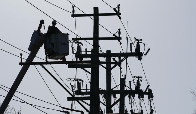 A worker works on the power lines in Annapolis, Md., on Dec. 15, 2021. Extremist groups in the United States appear to increasingly view attacking the power grid as a means of disrupting the country, according to a government report aimed at law enforcement agencies and utility operators.(AP Photo/Susan Walsh, File)