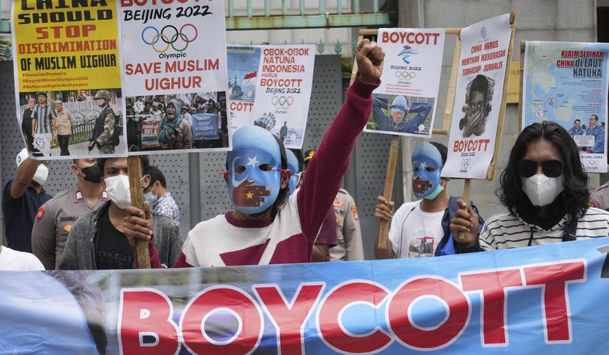Student activists, some wearing masks with the colors of the pro-independence East Turkistan flag, shout slogans during a rally to protest the Beijing 2022 Winter Olympic Games, outside the Chinese Embassy in Jakarta, Indonesia on Jan. 14, 2022. The 2022 Beijing Winter Olympics open in just over a week. When Beijing held the Summer Olympics in 2008 the International Olympic Committee predicted they could improve human rights, and Chinese politicians hinted at the same. There are no soaring promises this time. (AP Photo/Tatan Syuflana, File)