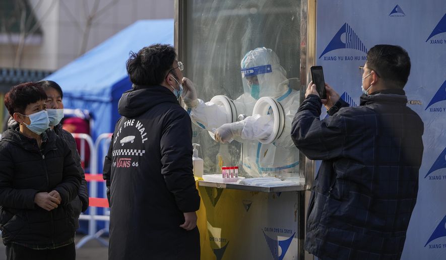 A man uses a smartphone to record residents getting a throat swab at a mass coronavirus test site in Xichen District in Beijing, Tuesday, Jan. 25, 2022. Hong Kong has already suspended many overseas flights and requires arrivals be quarantined, similar to mainland China&#39;s &amp;quot;zero-tolerance&amp;quot; approach to the virus that has placed millions under lockdowns and mandates mask wearing, rigorous case tracing and mass testing. (AP Photo/Andy Wong)