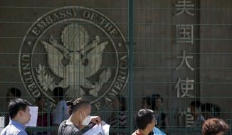 FILE - In this July 26, 2018 file photo visa applicants wait to enter the U.S. Embassy in Beijing, China. The U.S. Homeland Security Department says more than 700,000 foreigners who were supposed to leave the country during a recent 12-month period overstayed their visas. The department said in annual report Tuesday, Aug. 7, 2018, that there were 701,900 overstays from October 2016 through September 2017 among visitors who arrived by plane or ship. (AP Photo/Ng Han Guan, File)