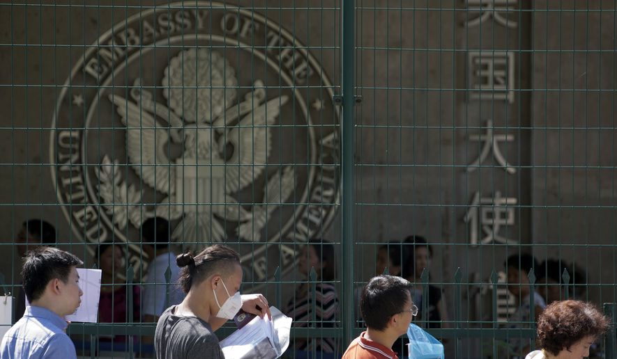 FILE - In this July 26, 2018 file photo visa applicants wait to enter the U.S. Embassy in Beijing, China. The U.S. Homeland Security Department says more than 700,000 foreigners who were supposed to leave the country during a recent 12-month period overstayed their visas. The department said in annual report Tuesday, Aug. 7, 2018, that there were 701,900 overstays from October 2016 through September 2017 among visitors who arrived by plane or ship. (AP Photo/Ng Han Guan, File)