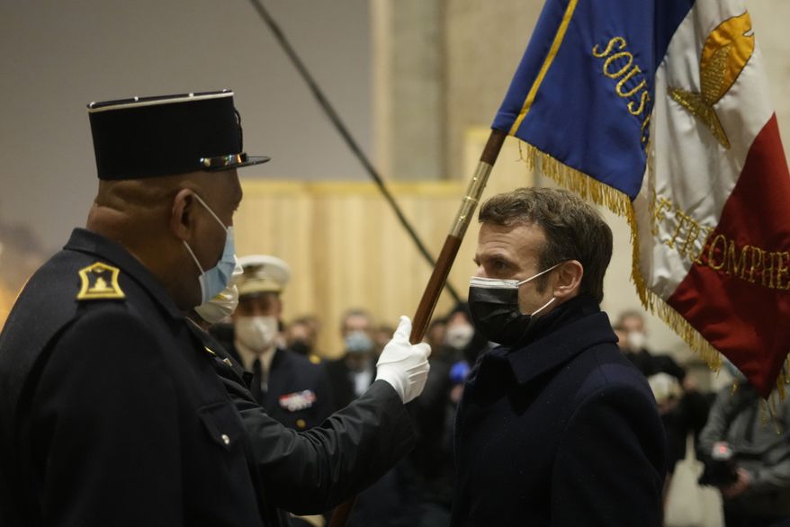 French President Emmanuel Macron, right, attends a ceremony at the Tomb of the Unknown Soldier under the Arc de Triomphe to mark the International Holocaust Remembrance Day, Thursday, Jan. 27, 2022, in Paris. Holocaust survivors and politicians warned about the resurgence of antisemitism and Holocaust denial as the world remembered Nazi atrocities and commemorated the 77th anniversary of the liberation of the Auschwitz concentration camp on Thursday. (AP Photo/Thibault Camus, Pool)