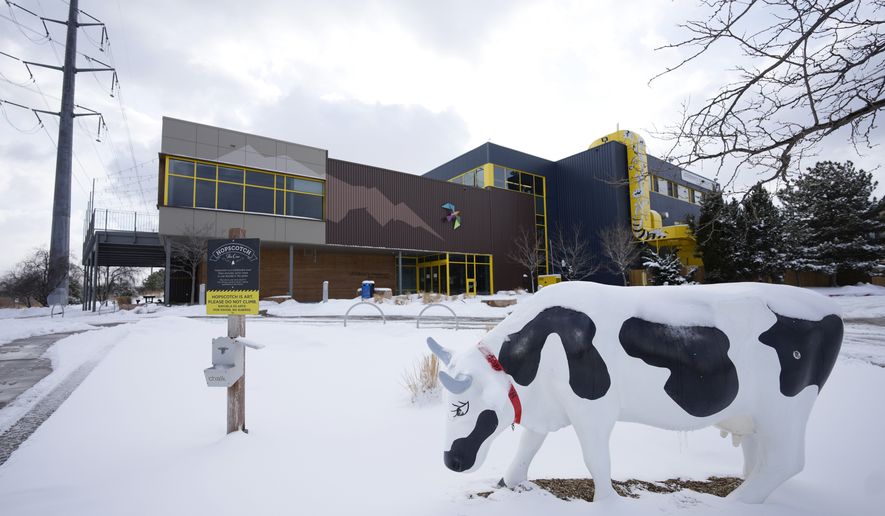 Hopscotch, a chalkboard cow, stands alone in a light snow outside the Children&#39;s Museum of Denver at Marsico Campus Thursday, Jan. 27, 2022, in Denver. The popular museum temporarily closed on Wednesday because of escalating harassment of staff by adult visitors angry over a city-ordered mandate requiring anyone age 2 and older to wear a mask in indoor public spaces. The museum will remain closed until Friday, Feb. 4. (AP Photo/David Zalubowski)