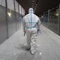A member of airport personnel dressed in protective gear leads passengers into the customs area at the Beijing Capital International Airport ahead of the 2022 Winter Olympics in Beijing, Jan. 24, 2022. (AP Photo/Jae C. Hong, File)