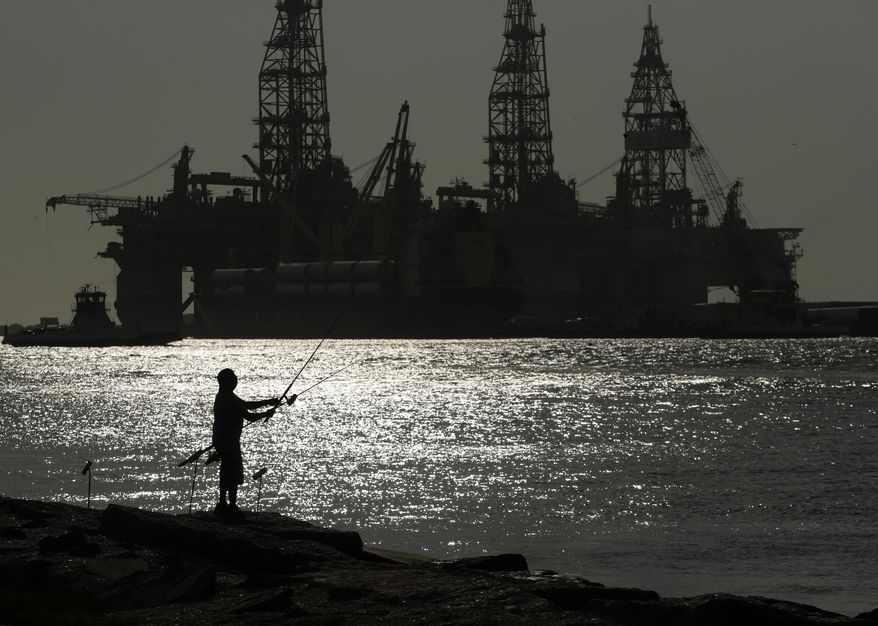 A man wears a face mark as he fishes near docked oil drilling platforms, on May 8, 2020, in Port Aransas, Texas. A federal court has rejected a proposed lease auction for offshore oil drilling in the Gulf of Mexico, saying the Biden administration failed to conduct a proper environmental review. The decision on Jan. 27, 2022, by U.S. District Judge Rudolph Contreras sends the proposed lease sale back to the Interior Department to decide next steps. (AP Photo/Eric Gay, File)