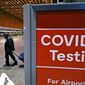 FILE - Travelers pass a sign near a COVID-19 testing site in Terminal E at Logan Airport, on Dec. 21, 2021, in Boston. A new AP-NORC poll shows that few Americans – just 15% – say they&#39;ll consider the pandemic over only when COVID-19 is largely eliminated. By contrast, 83% say they&#39;ll feel like the pandemic is over when it&#39;s largely a mild illness, like the seasonal flu. (AP Photo/Charles Krupa, File)