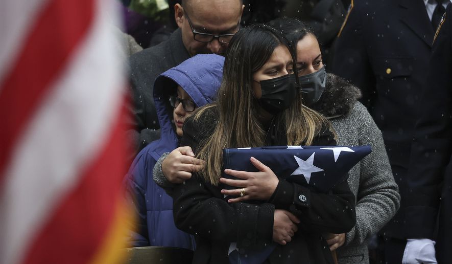 Dominique Rivera, left, wife of, NYPD Officer Jason Rivera watches as his casket is loaded into a hearse outside St. Patrick&#x27;s Cathedral after his funeral service, Friday, Jan. 28, 2022, in New York. Rivera and his partner, Officer Wilbert Mora, were fatally wounded when a gunman ambushed them in an apartment as they responded to a family dispute last week. (AP Photo/Yuki Iwamura)