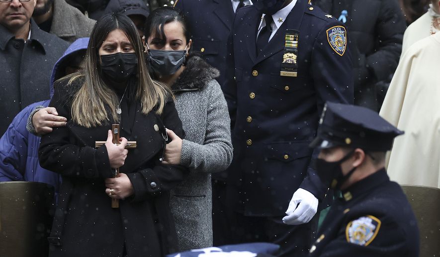 Dominique Rivera, left, widow of, NYPD Officer Jason Rivera waits to be presented with a flag after Rivera&#39;s funeral outside St. Patrick&#39;s Cathedral, Friday, Jan. 28, 2022, in New York. Rivera and his partner, Officer Wilbert Mora, were fatally wounded when a gunman ambushed them in an apartment as they responded to a family dispute last week. (AP Photo/Yuki Iwamura)