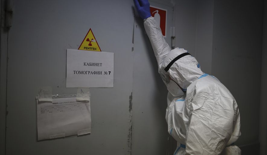 A medical staff member leans on a door while a patient with COVID-19 gets through a Magnetic resonance imaging system at an ICU of an hospital in Krasnodar, southern Russia, Thursday, Jan. 27, 2022. Russia has confirmed 11,404,617 cases of coronavirus and 328,770 deaths, according to the national coronavirus information center. Russia's total excess fatality count since the start of the coronavirus pandemic is at least 929,000. Under half the population is fully vaccinated. (AP Photo/Vitaliy Timkiv)