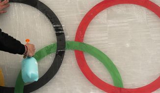An ice maker sprays water over a cutout of the Olympic rings while installing a sub-glacial Beijing 2022 logo on the track at the Yanqing National Sliding Center ahead of the 2022 Winter Olympics, Friday, Jan. 28, 2022, in the Yanqing district of Beijing. (AP Photo/Jae C. Hong)