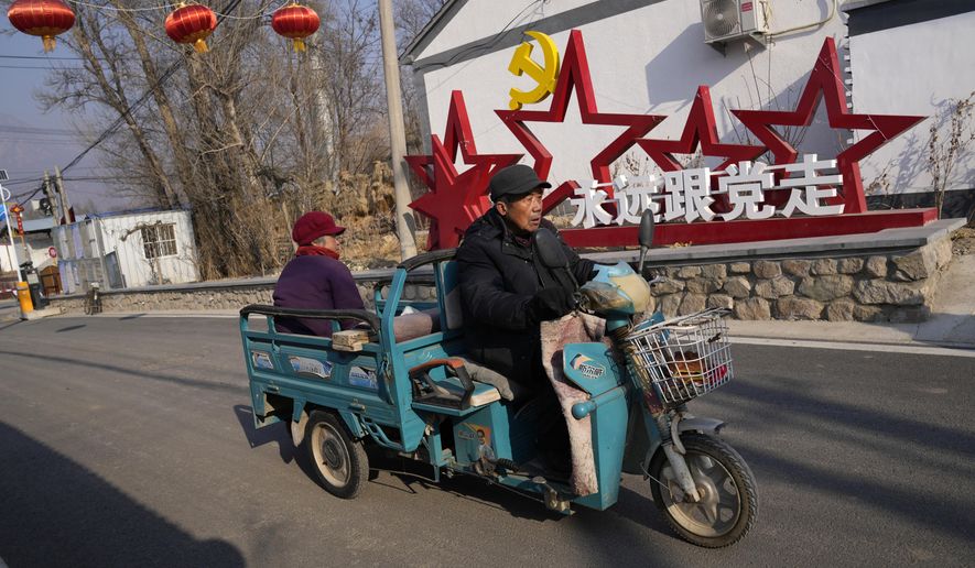 Local residents past by a sign which reads &amp;quot;Forever follow the Communist Party&amp;quot; at Houheilong Miao, a village in Yanqing on the outskirts of Beijing, China, Wednesday, Jan. 5, 2022. The village has a view of the Olympics skiing venue in the distance. Its 20 mostly vacant traditional courtyard houses have been turned into lodgings and a cafe dubbed the &amp;quot;Winter Olympic Home.&amp;quot; (AP Photo/Ng Han Guan)