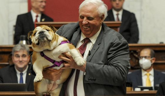 West Virginia Gov. Jim Justice holds up his dog Babydog as he comes to the end of his State of the State speech in the House chambers, at the West Virginia State Capitol in Charleston, W.Va., Thursday, Jan. 27, 2022. (Chris Dorst/Charleston Gazette-Mail via AP)