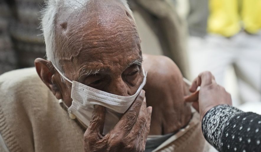 An elderly man receives a COVID-19 vaccination at a makeshift center in a government school in New Delhi, India, Friday, Jan. 28, 2022. Indian health officials said that the first signs of COVID-19 infections plateauing in some parts of the vast country were being seen, but cautioned that cases were still surging in some states. (AP Photo/Manish Swarup)