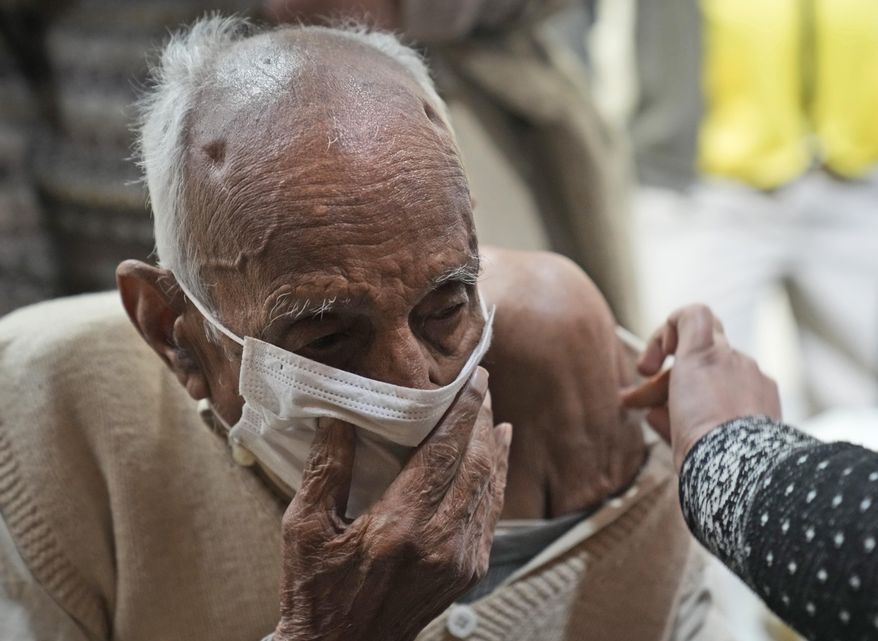 An elderly man receives a COVID-19 vaccination at a makeshift center in a government school in New Delhi, India, Friday, Jan. 28, 2022. Indian health officials said that the first signs of COVID-19 infections plateauing in some parts of the vast country were being seen, but cautioned that cases were still surging in some states. (AP Photo/Manish Swarup)